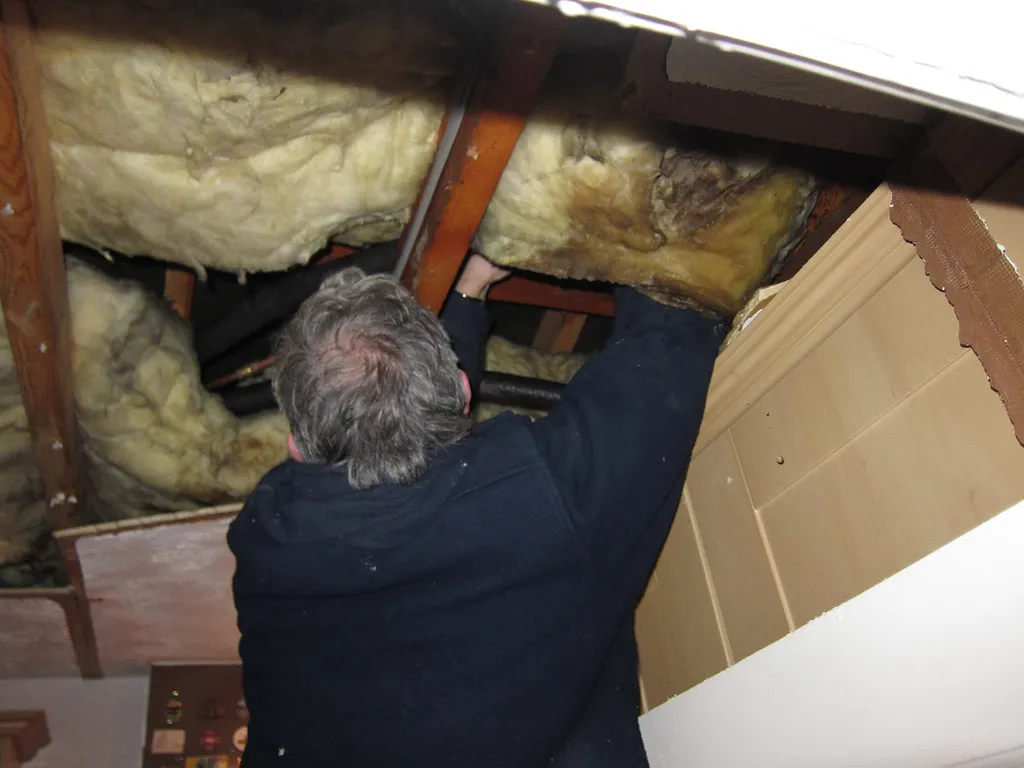 Plumber making a repair to overhead residential pipes