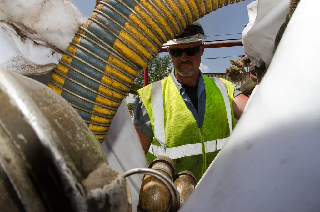 Crew operating a sewer vacuum hose during line service